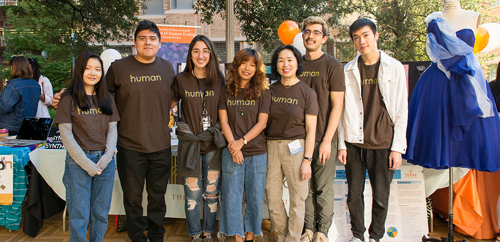 A group of human ecology students smile at a fair